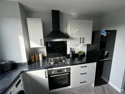a kitchen with white cabinets and a black refrigerator at ClydeBank Brand new 3BDR Home, Glasgow in Clydebank