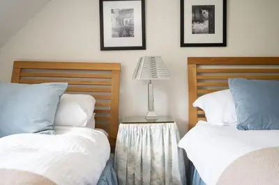 a bedroom with two beds and a lamp on a table at The Coach House in Saint Fillans