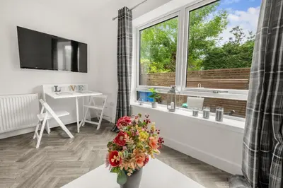 a living room with a window and a vase of flowers at Beautiful 1 BR apt with private patio and free parking in Dunollie