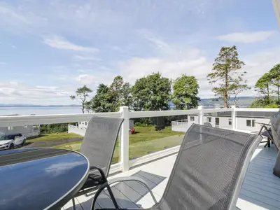 a table and chairs on a deck with a view of the ocean at Bethany's Retreat in Wemyss Bay