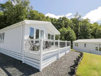 a white tiny house with a deck at Bethany's Retreat in Wemyss Bay