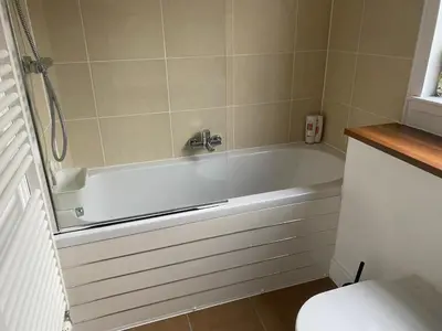 a bathroom with a white tub and a toilet at The Pentland Apartment in Penicuik