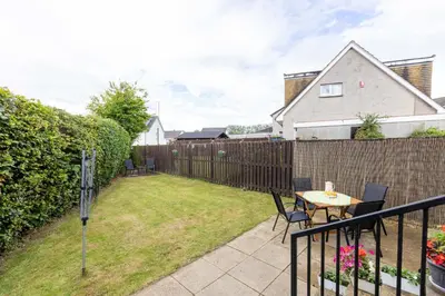 a backyard with a fence and a table and chairs at 20 mins to Edinburgh 3 bedroom detached family house Wi-Fi Parking in Fife