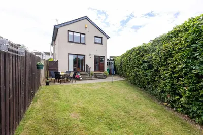 a white house with a fence and a yard at 20 mins to Edinburgh 3 bedroom detached family house Wi-Fi Parking in Fife