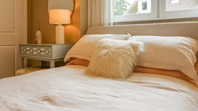a bed with a white comforter and a window at Modern And Cozy Apex Apartment in Helensburgh