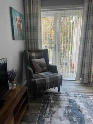 a living room with a chair and a window at Loch Lomond Riverside Apartments A in Balloch