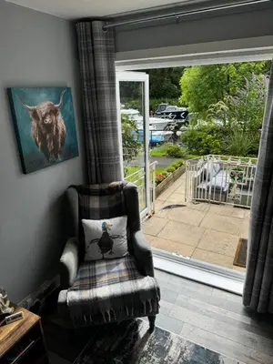 a living room with a chair and a window at Loch Lomond Riverside Apartments A in Balloch