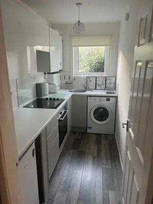 a kitchen with a sink and a washing machine at Loch Lomond Riverside Apartments A in Balloch