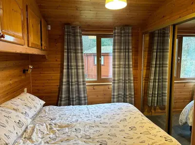 a bedroom with a bed in a log cabin at Lomond View Lodge in Glasgow