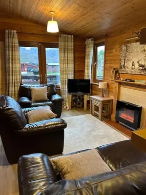 a living room with leather furniture and a fireplace at Lomond View Lodge in Glasgow