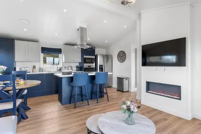 a kitchen and living room with blue chairs and a fireplace at Arrochar View in Langbank