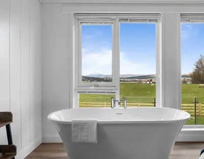 a white bath tub in a bathroom with two windows at Arrochar View in Langbank