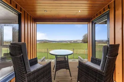 a screened in porch with a table and chairs at Arrochar View in Langbank
