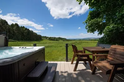 a hot tub and a table and chairs on a deck at Argyll View in Langbank