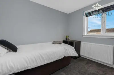 a bedroom with a large bed and a window at Brand New 4 Bedroom House - Sleeps 4 Fully Equipped, Free Parking, WiFi, Perfect for CONTRACTORS by Diamond Short Lets in Rosyth