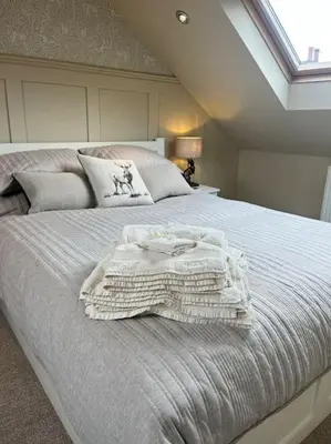 a bed with a white blanket on top of it at Kirkton Rest in Cardross