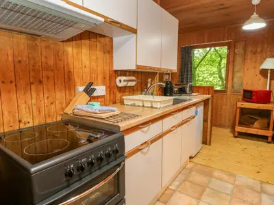 a kitchen with wooden walls and a stove top oven at Lodge 3 - 