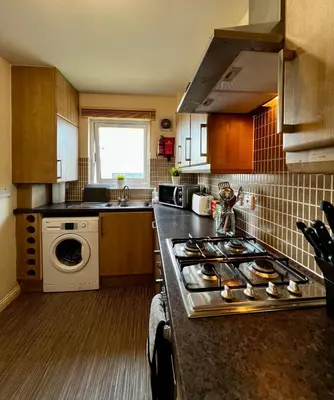 a kitchen with a stove top oven next to a sink at Stylish Modern Flat with Juliet Balcony & Parking in Glasgow