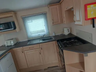 a small kitchen with a sink and a stove at Victoria's Caravans in Ayr