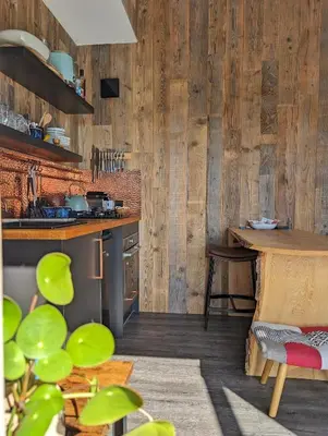 a kitchen with wooden walls and a wooden table at Otter Burn Cabin in Oban