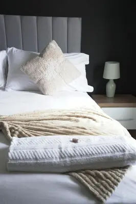 a bed with white blankets and pillows on it at Andrew House in Bathgate
