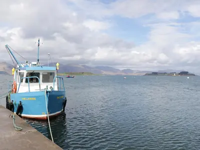 a blue boat tied to a dock in the water at Tirlaggan House in Oban