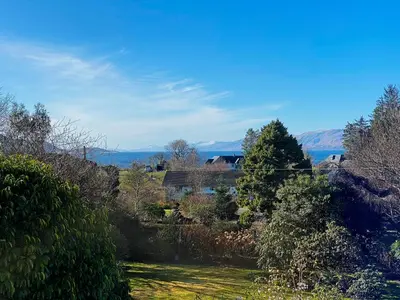 a view of a yard with trees and the water at The Garden Flat in Fort William