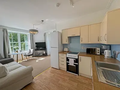 a kitchen with a white refrigerator and a living room at The Garden Flat in Fort William