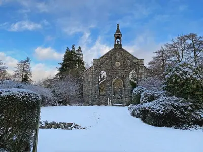 an old stone church with a clock tower in the snow at The Garden Flat in Fort William