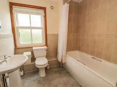 a bathroom with a toilet and a tub and a sink at Knightsridge House in Livingston