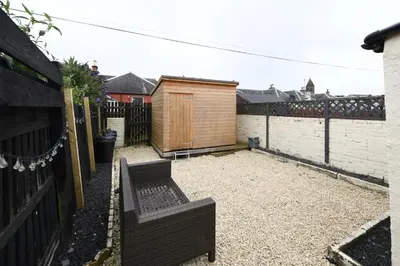 a backyard with two benches and a fence at Hunter Links Cottage in Prestwick