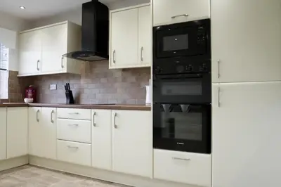 a kitchen with white cabinets and black appliances at Rhyber Avenue in Lanark