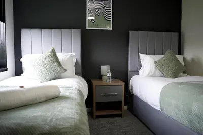 a bedroom with two beds and a table with a bottle of water at Calgary House in Livingston