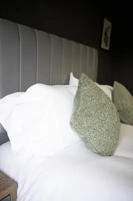 a white bed with green pillows on it at Calgary House in Livingston