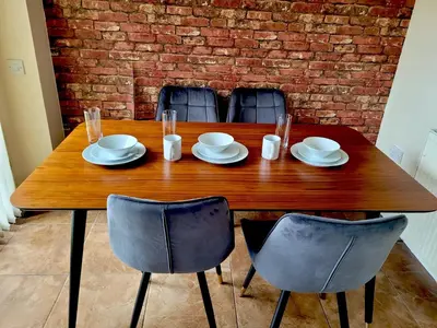 a wooden table with chairs and plates and glasses at Glasgow Central - Entire house - Free Parking , Free super fast Wifi , Private garden & Parking security in Govan