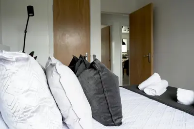 a bedroom with a bed with pillows on it at Sunnyside Penthouse in Coatbridge