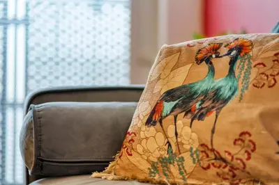 a pillow with peacocks on it sitting on a couch at Modern 2 Bed Flat with Free Parking in Glasgow
