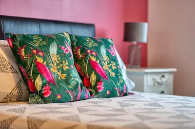 a green pillow sitting on top of a bed at Modern 2 Bed Flat with Free Parking in Glasgow