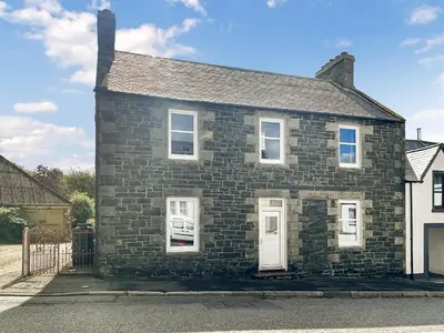 an old brick house with white doors on a street at Arden in Glenluce