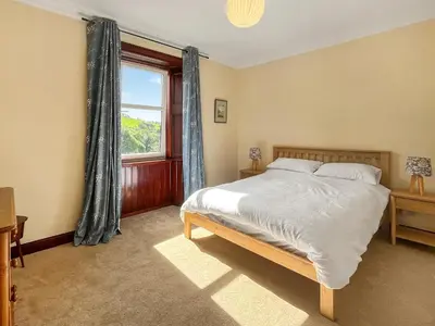 a bedroom with a large bed and a window at Arden in Glenluce