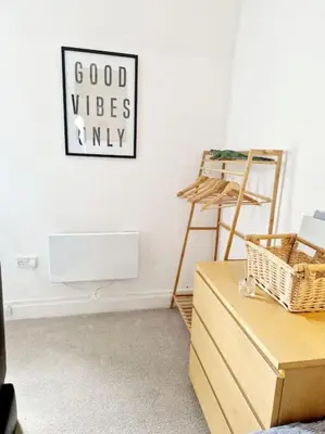 a room with a white wall with a sign that reads good vibes only at Cumbrae Loft in Millport