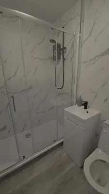 a white bathroom with a shower and a toilet at Cumbrae Loft in Millport