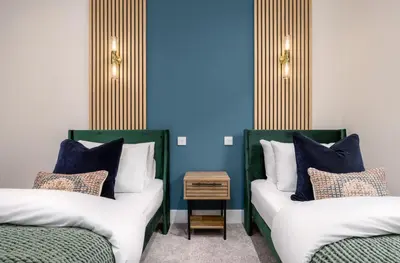 two beds in a room with blue walls at City Centre Haven Apartment in Stirling