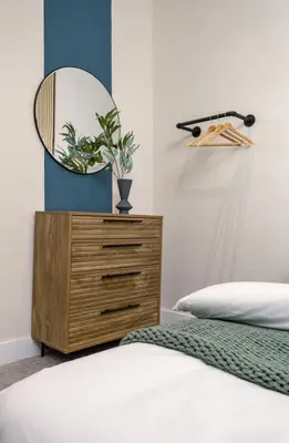 a bedroom with a dresser with a mirror on it at City Centre Haven Apartment in Stirling