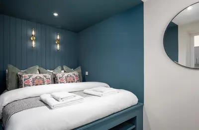 a blue bedroom with a large bed with a mirror at City Centre Haven Apartment in Stirling
