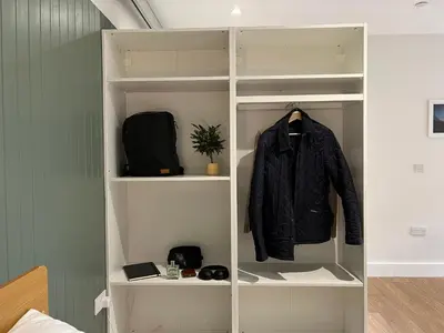 a white book shelf with a jacket in it at Modern Accessible Apartment with Interconnecting Room in Dolphinton