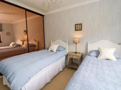 a bedroom with two beds and a table with a lamp at Mousebank in Lanark