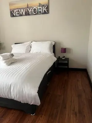 a bedroom with a large white bed with a wooden floor at One Bedroom Apartment in Gorgie with new central heating system in Edinburgh