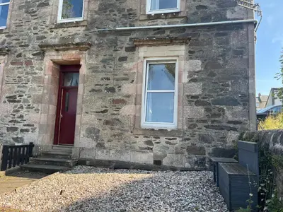 an old stone house with a red door at Our Wee Eden - Rothesay in Rothesay