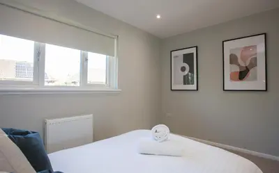 a bedroom with a bed with a alarm clock on it at Stylish and Modern 2 Bed House in Glasgow